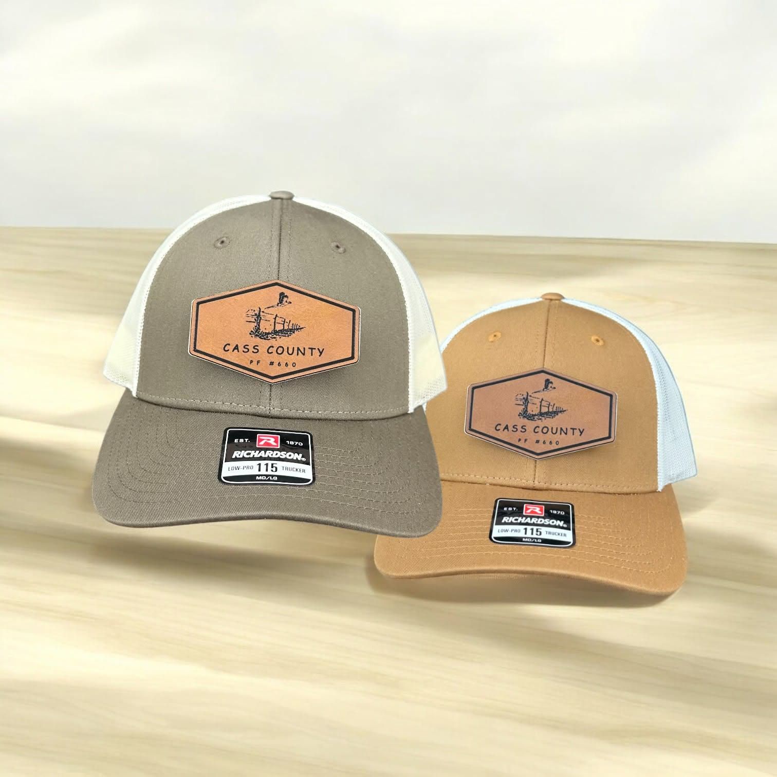 Two trucker hats with engraved leatherette Cass County patches