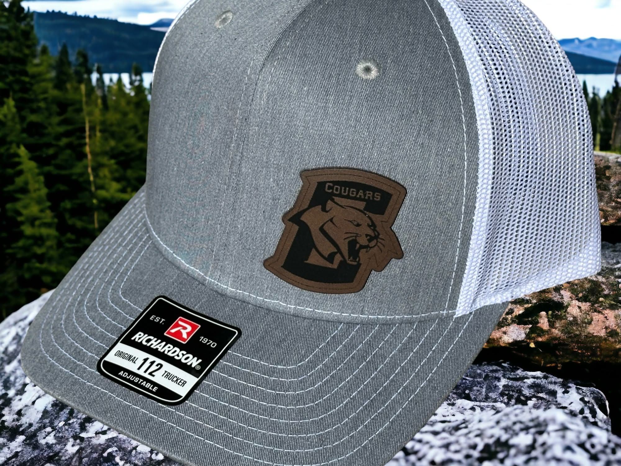 Heather trucker hat with an engraved leatherette Conestoga Cougars patch