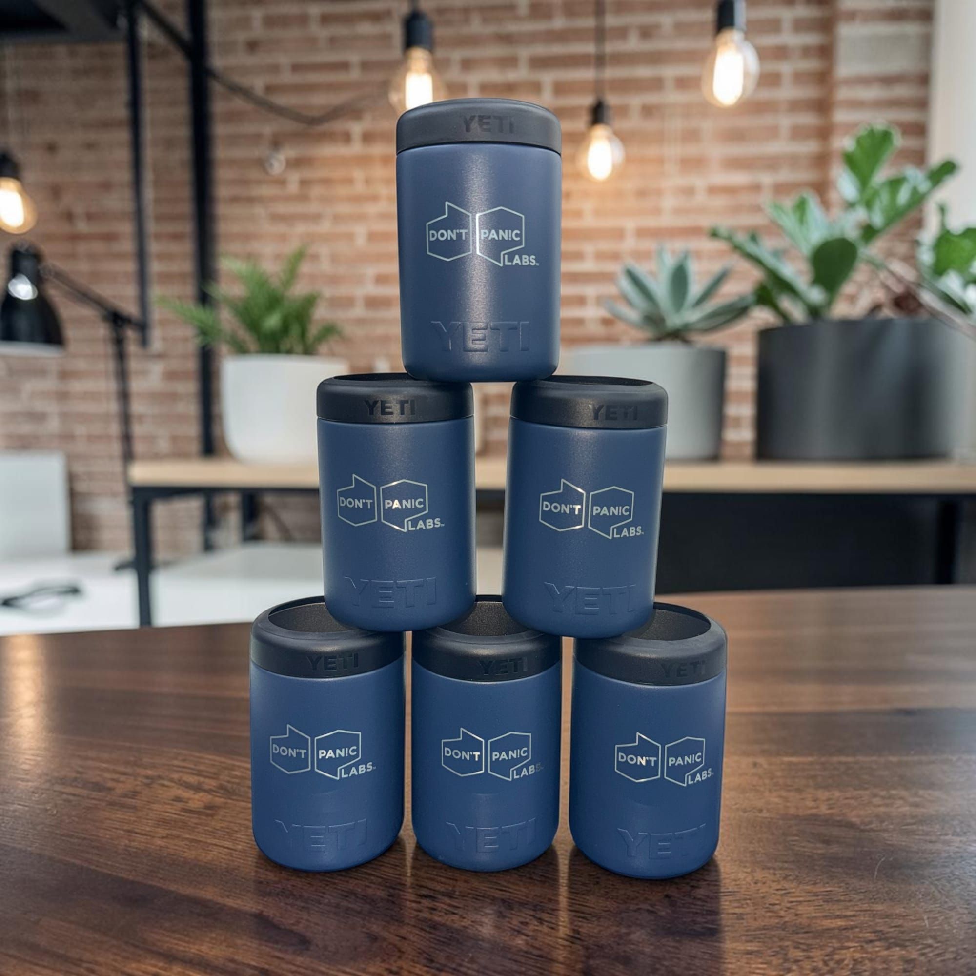 Pyramid of navy YETI can coolers engraved with the Don't Panic Labs logo in an office