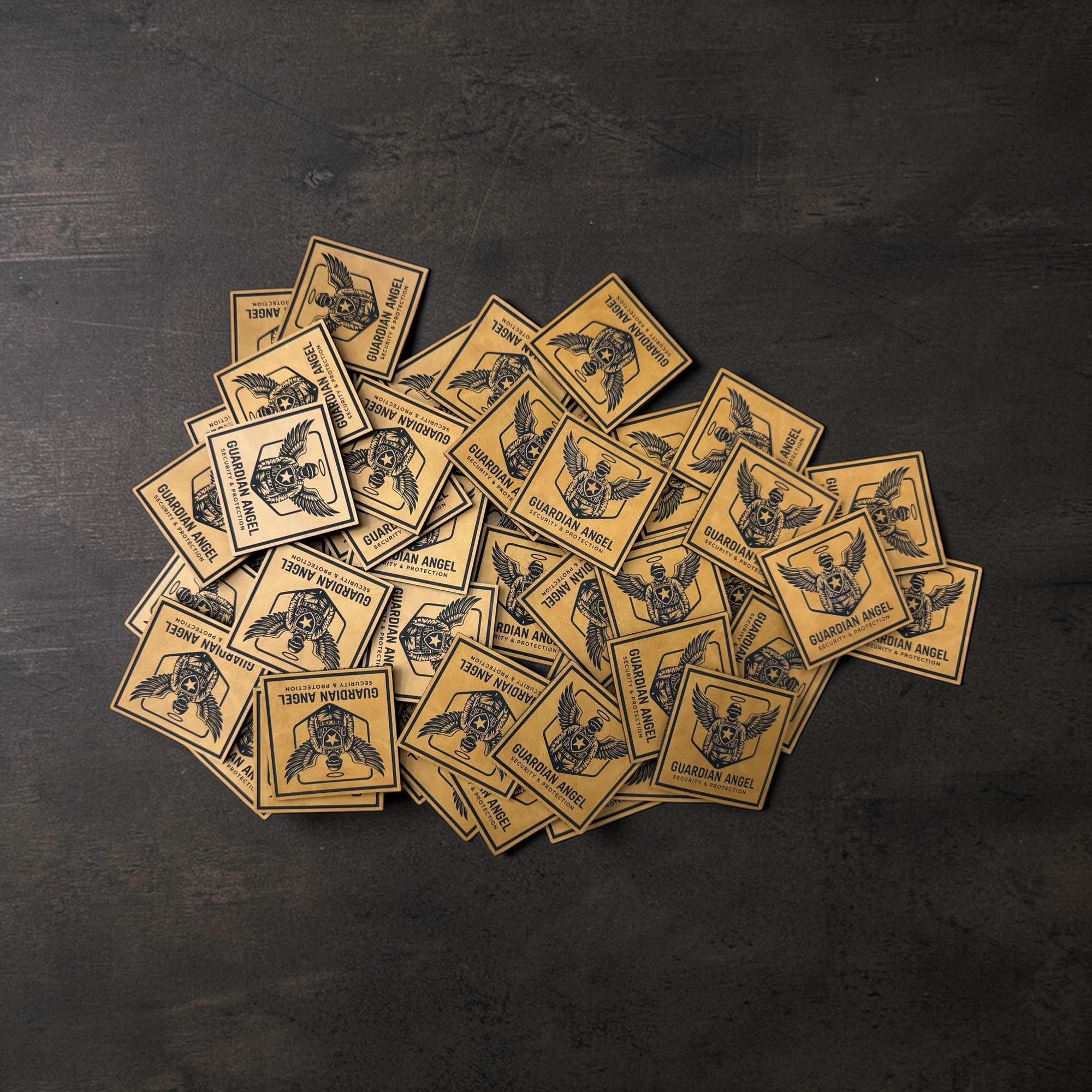 Pile of engraved leatherette Guardian Angel security patches