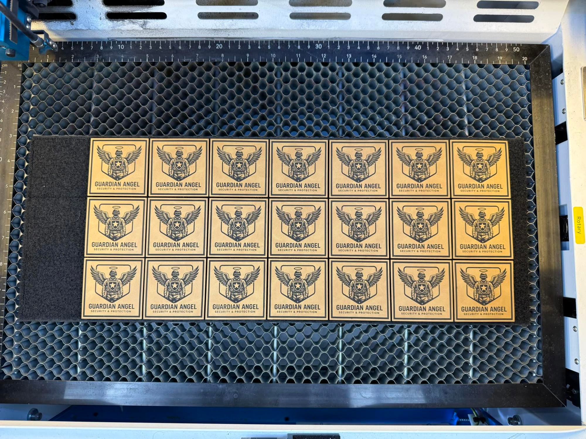 Sheet of freshly engraved leatherette patches on the laser honeycomb bed