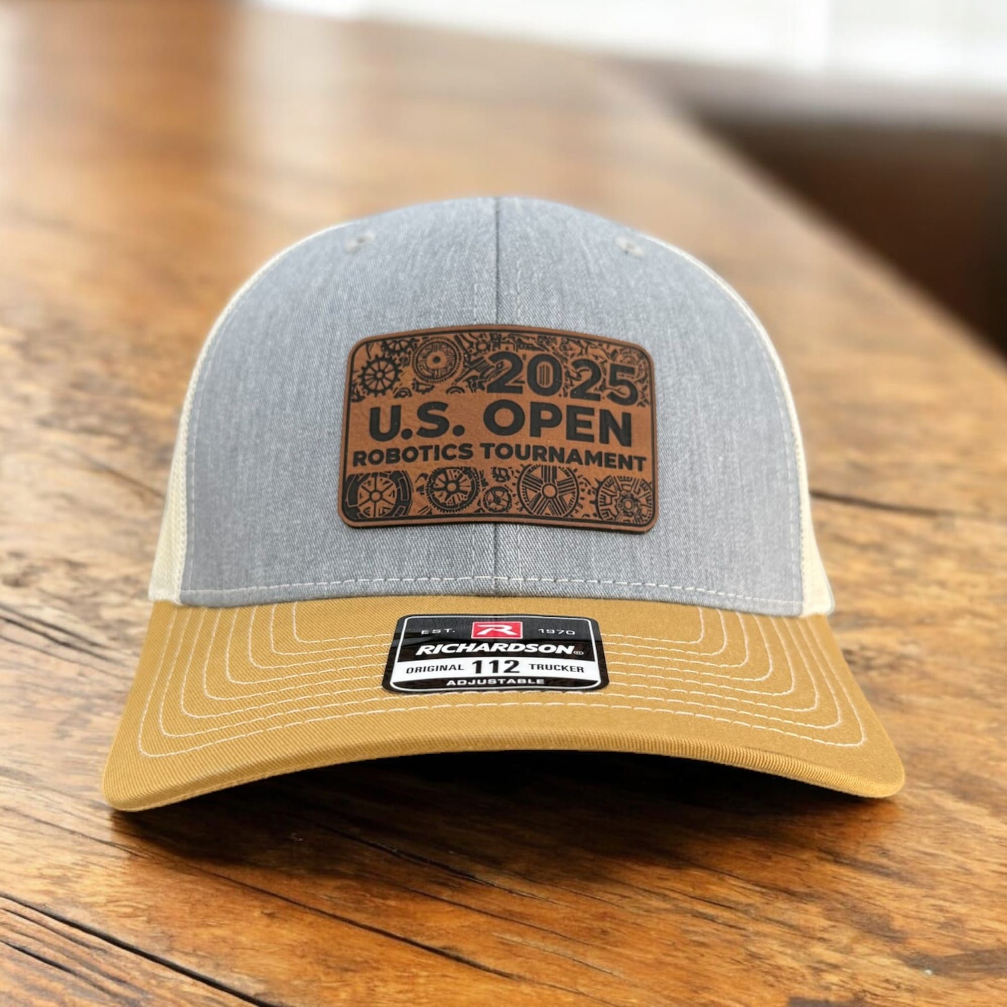 Heather grey Richardson 112 with a gold brim and an engraved 2025 U.S. Open Robotics Tournament leatherette patch
