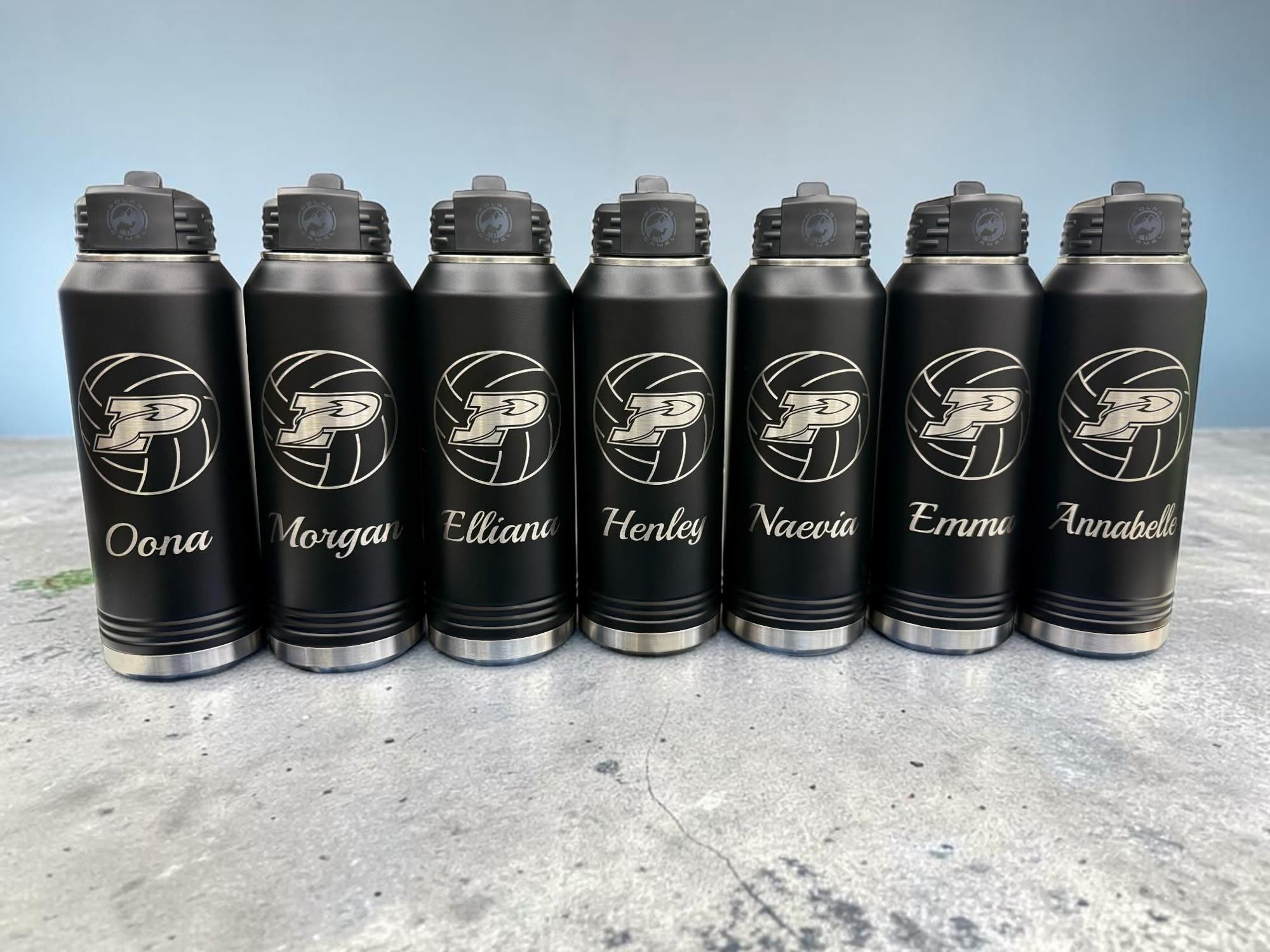 Seven black water bottles engraved with a volleyball P logo and player names